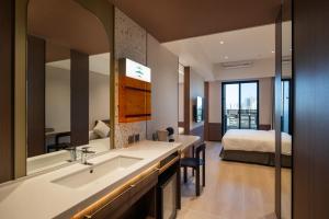 a bathroom with a sink and a bed in a room at Boutech hotel Banqiao Yellowstone in Taipei