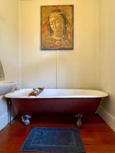 a bath tub in a bathroom with a painting on the wall at Wisteria Villa in Russell +21 photos