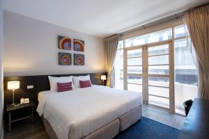 a bedroom with a bed and a large window at 24 Inn at BTS Phrom Phong in Bangkok