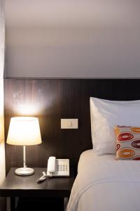 a hotel room with a bed and a phone on a table at 24 Inn at BTS Phrom Phong in Bangkok