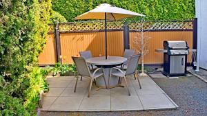 a table and chairs with an umbrella and a grill at Svitanok in Victoria