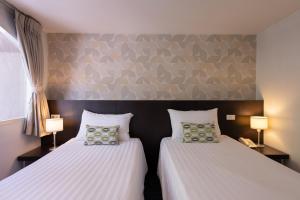 two beds sitting next to each other in a bedroom at 24 Inn at BTS Phrom Phong in Bangkok