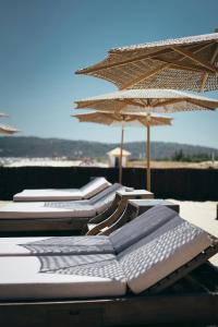 a row of lounge chairs with umbrellas on a beach at Villa Argonaute in Saint-Tropez