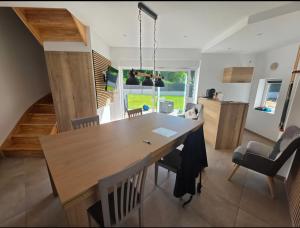 a dining room and kitchen with a wooden table and chairs at Le Petit L Orée des Bois in Blainville-sur-lʼEau