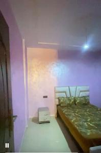 a bedroom with a bed and a purple wall at منزل شامة in Moulay Yacoub