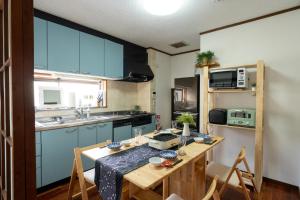 a kitchen with blue cabinets and a wooden table at オーシャンステイみうら in Miura