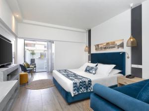 a bedroom with a blue and white bed and a couch at Mercure Rhodes Alexia Hotel & Spa in Rhodes Town