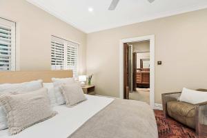a white bedroom with a bed and a couch at Antara House by Coast Hosting in Matcham