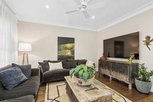 a living room with a couch and a tv at Antara House by Coast Hosting in Matcham