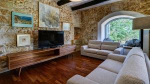 a living room with a tv and a stone wall at Wonderful 4BR Farmhouse with Private Pool in Rabat