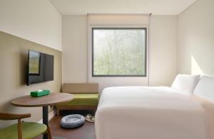 a hotel room with a bed and a window at Go Hotel Nakhon Sawan in Ban Pak Nam Pho