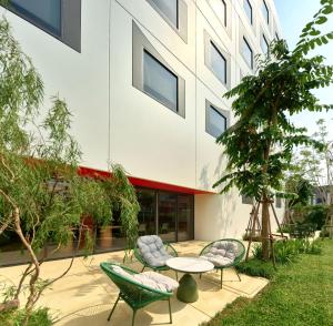 a patio with chairs and a table in front of a building at Go Hotel Nakhon Sawan in Ban Pak Nam Pho