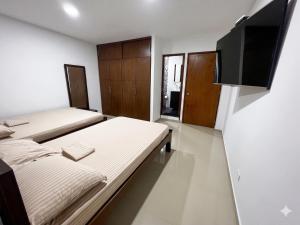 a bedroom with two beds and a flat screen tv at Casa del Prado in Cali