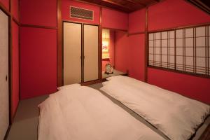 a bedroom with red walls and a white bed at Hikoso-machi Kin no Ma in Kanazawa