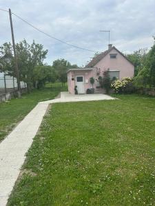 a small pink house with a grass yard at Apartman Marcel in Nijemci