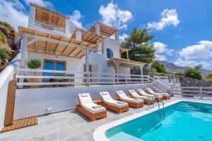 a villa with a swimming pool and lounge chairs at Epsilon Apartments in Kalymnos