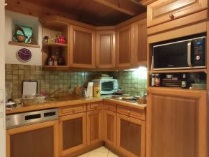 a kitchen with wooden cabinets and a microwave at Nice cottage in Brittany in Plouigneau +8 photos