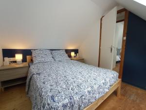 a bedroom with a bed with a blue and white comforter at Nice cottage in Brittany in Plouigneau
