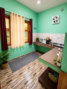 a kitchen with green walls and wooden floors at Adarsh homestay - 1BHK in Manāli