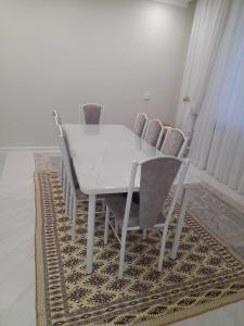 a white dining room table and chairs on a rug at Guest House Maral in Bokonbayevo