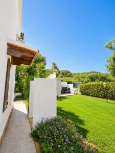 a white house with a yard with flowers at SweetHouse Pula in Porto Columbu - Perdʼe Sali