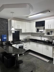 a kitchen with white cabinets and a black counter top at Rondon Sunset Belas Artes - 3Q - 3 salas - Sacada in Uberlândia