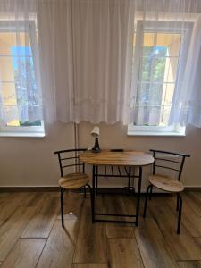 a table and chairs in a room with two windows at Centrum Noclegowe II in Bydgoszcz +48 photos