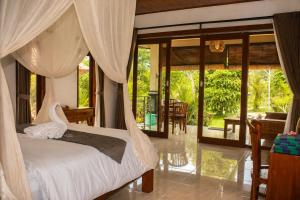 a bedroom with a bed and a room with a patio at Papahan Bali in Sidemen