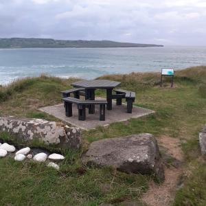 a picnic table sitting on the side of the ocean at Teach Caitlin in Ballina