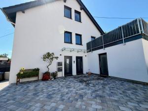 a white house with black doors and a patio at Ferienwohnung zum Buchfeld in Windesheim