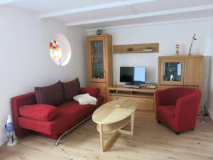 ein Wohnzimmer mit einem roten Sofa und 2 Stühlen in der Unterkunft Sonne in Elmenhorst