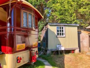 a red bus parked next to a tiny house at Molly the Showman's Wagon in Hailsham +14 photos
