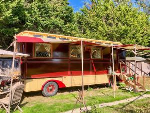 an old red and yellow bus parked in a yard at Molly the Showman's Wagon in Hailsham