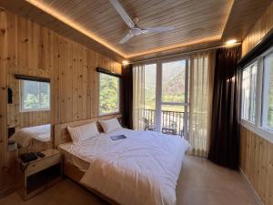 a bedroom with a bed in a room with windows at Hotel Dev Darshan in Uttarkāshi