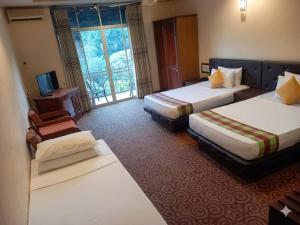a hotel room with two beds and a television at Hotel Lakefield in Kandy