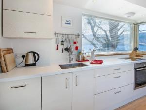 a white kitchen with a sink and a window at Dipper Boathouse in Acharn