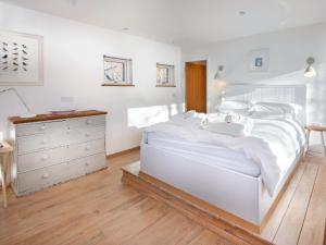a white bedroom with a large bed and a dresser at Dipper Boathouse in Acharn +2 photos