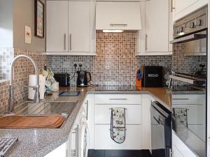 a kitchen with white cabinets and a sink at Dihangfa Wylau in Tywyn
