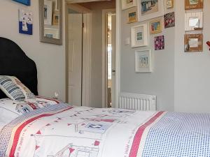 a bedroom with a bed with a comforter on it at Dihangfa Wylau in Tywyn +6 photos