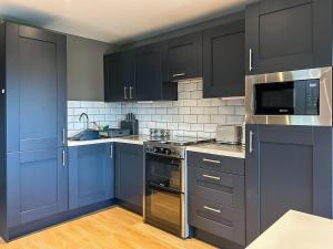 a kitchen with dark blue cabinets and appliances at Bellstane Chalet - Ukc9440 in Glasgow