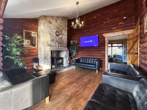 a living room with leather furniture and a stone fireplace at Bellstane Chalet - Ukc9440 in Glasgow