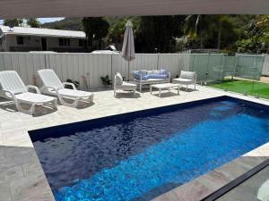 a swimming pool with chairs and a table and an umbrella at Flip flops in Horseshoe Bay