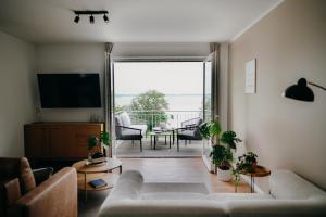 a living room with a couch and a television and a balcony at Bei Plön mit Seeblick und großem Balkon in Dersau