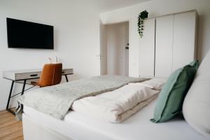 a white bedroom with a bed and a desk at Bei Plön mit Seeblick und großem Balkon in Dersau