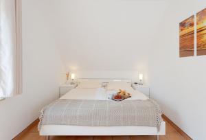 a white bedroom with a bed with a bowl of fruit on it at MEERerholung in Zinnowitz