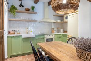a kitchen with green cabinets and a wooden table at Cal Moline Arrels - Refugio rural de diseño en el Berguedà in Graugés