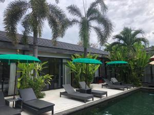 a group of chairs and umbrellas next to a pool at Le Chien Rouge in Lovina