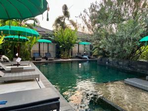 a pool with chairs and umbrellas in a resort at Le Chien Rouge in Lovina