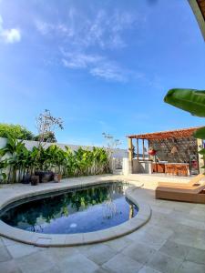 a swimming pool in a yard with a patio at Juna Guest House in Uluwatu