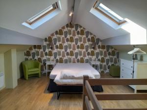 a bedroom with a bed and a green chair at Le Cerf volant in Libin